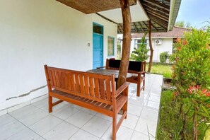 A wooden bench and table under a pergola on a tiled patio. - Hepi Bungalow Lovina Mitra RedDoorz (Bali)