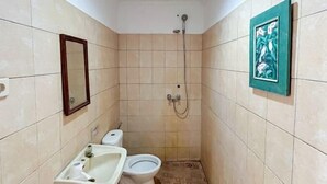 A small bathroom with a toilet, sink, and shower.