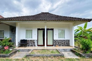 Uma casa de dois andares com telhado de telhas, varanda frontal e um pequeno jardim.