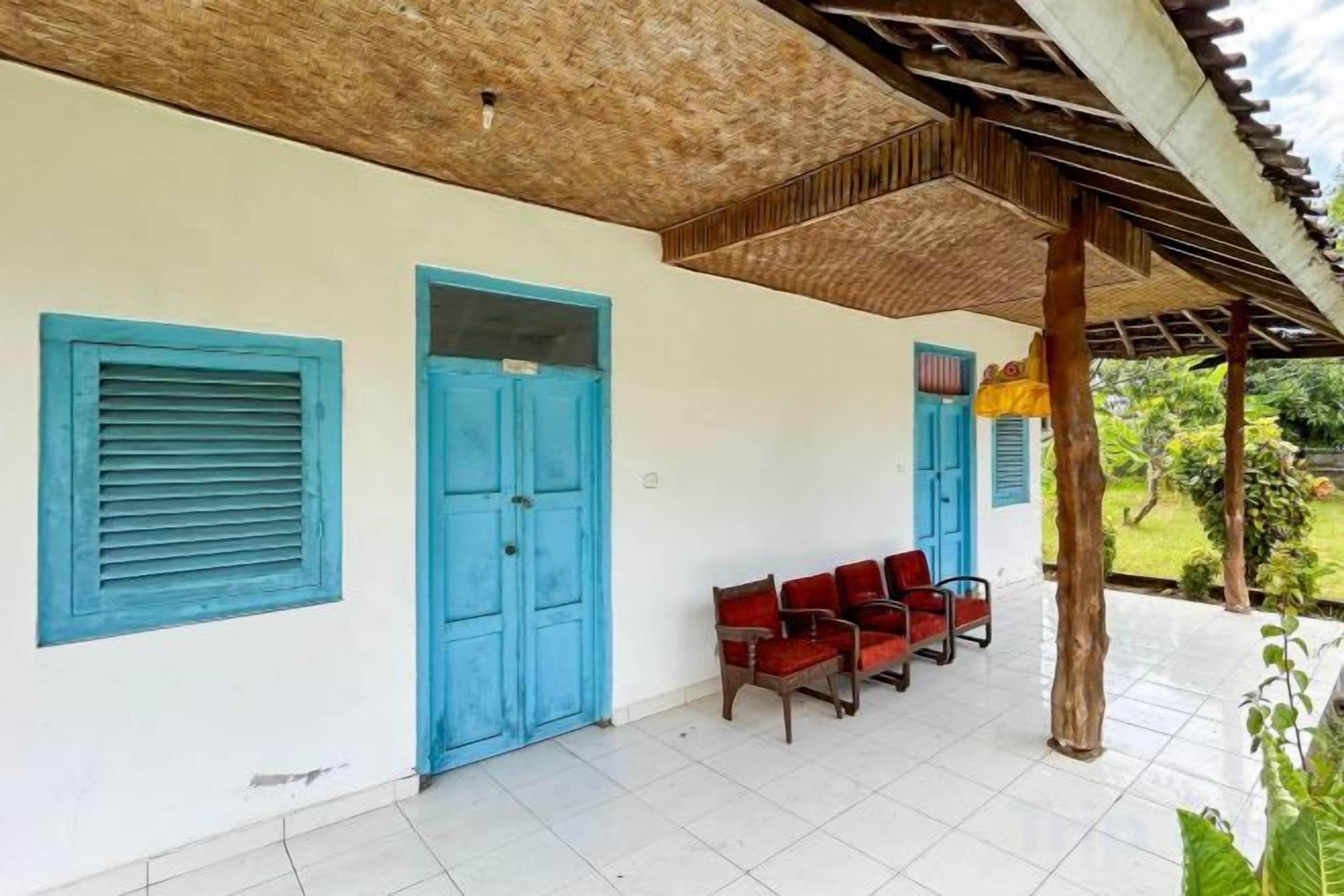 A covered outdoor seating area with blue doors and red chairs.