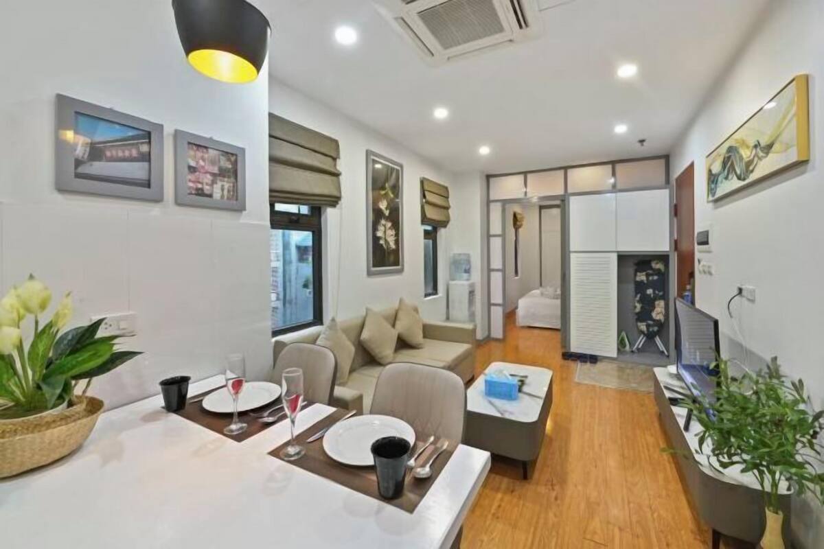 A modern hotel room with a dining area, a sofa, a TV, and a desk.