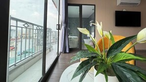 A balcony with a view of buildings, a potted plant, a flat-screen TV, and an air conditioning unit. - 22HOUSING SERVICE APARTMENT (Hanoi)