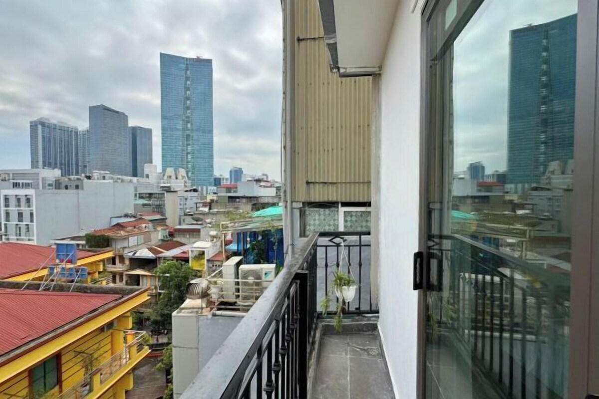 A balcony with a city view, a glass door, and a metal railing.