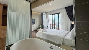 Una habitación de hotel moderna con una cama grande, una bañera y un balcón con vistas.