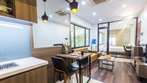 A modern hotel room with a dining area, a sofa, a bed, and a bathroom visible through a glass door. - 22HOUSING SERVICE APARTMENT (Hanoi)