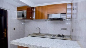 A kitchen with granite countertops, stainless steel appliances, and wooden cabinets. - Kigali Bliss Apartment (Kigali)
