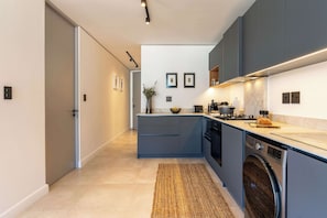Una cucina moderna con mobili grigi, una lavatrice integrata e un'isola centrale con un vaso e una ciotola.