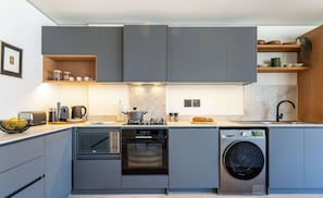 Una cucina moderna con mobili grigi, forno integrato, microonde ed elettrodomestici.
