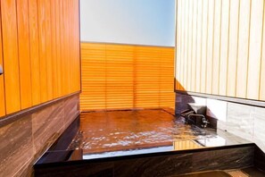 A modern bathroom with wooden paneling, a glass shower enclosure, and a marble countertop.