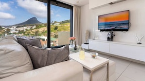A modern living room with a large window, a flat-screen TV, and a sofa.
