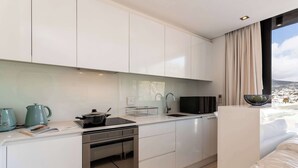 A modern kitchen with white cabinets, a built-in oven, and a window with a view of a cityscape.