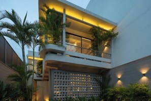 A modern building with multiple balconies, outdoor lighting, and lush greenery. - K.House Holiday Phan Thiet by Blue Fingers (Phan Thiet)