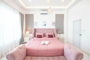 A bedroom with a pink bed, a nightstand, a lamp, and a wardrobe.
