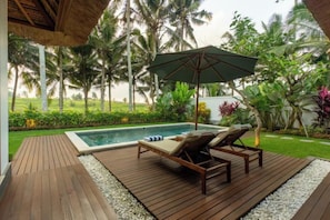 A wooden deck with a pool, lounge chairs, and an umbrella. - The Lanaya Villa (Bali)