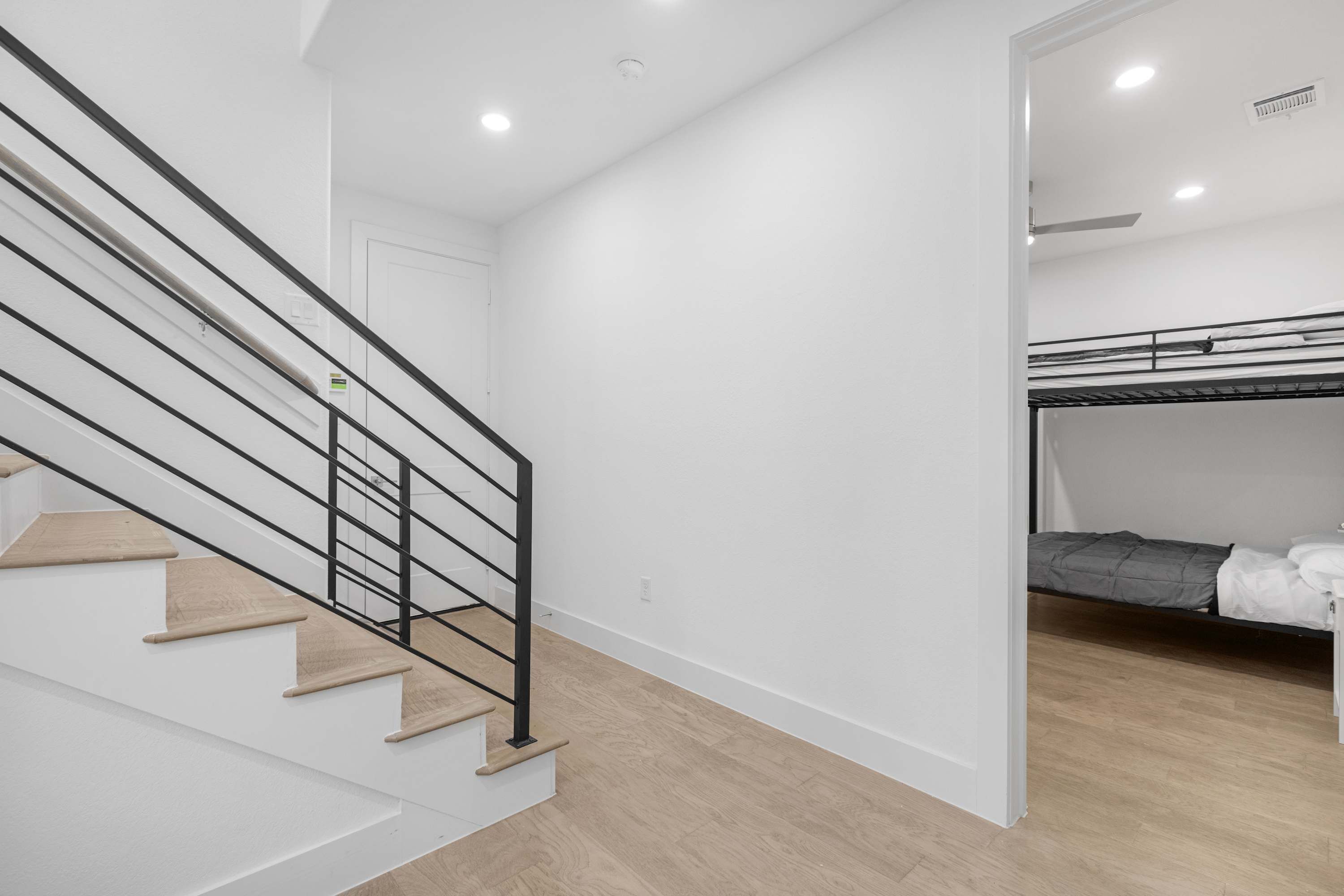 Un interior moderno con una escalera, una cama litera y una puerta blanca.