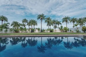 A swimming pool with palm trees and a clear sky. - Neoteric Resort Hotel (Viti Levu)