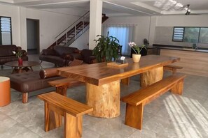 A spacious living area with a large wooden table and benches, a staircase, and a potted plant. - Neoteric Resort Hotel (Viti Levu)