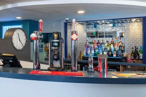 A bar area with multiple beer taps, a coffee machine, and a variety of liquor bottles. - Holiday Inn Express STAFFORD by IHG (Acton Trussell and Bednall)