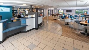 En modern hotellobby med en receptionsdisk, en sittgrupp och en klocka.