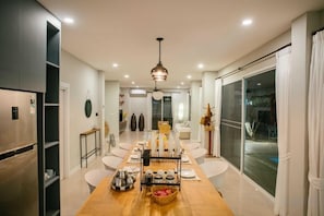 Une cuisine moderne avec un coin repas, comprenant une table en bois, des chaises blanches et une grande fenêtre.