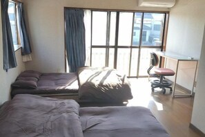 A room with two beds, a desk, and a chair. - Cherry Blossom House (Saitama)