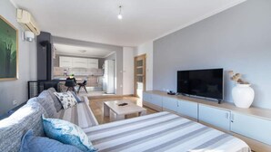 Un soggiorno moderno con un divano ampio, una televisione a schermo piatto e un'area pranzo con cucina sullo sfondo.