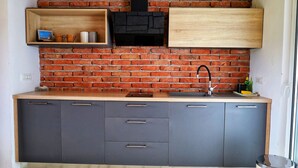 Una cucina con parete in mattoni, ripiano in legno, cappa aspirante nera e lavello in acciaio inossidabile.