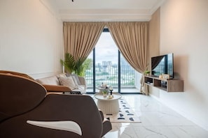 A modern living room with a sofa, a coffee table, and a TV on a stand. - CUBIC BOTANICAL BY FEEL HOME (Kuala Lumpur)