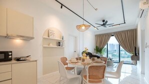 A modern kitchen with white cabinets, a dining area with a round table and white chairs, and a large window with curtains. - CUBIC BOTANICAL BY FEEL HOME (Kuala Lumpur)