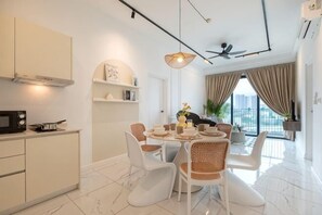 A modern kitchen with white cabinets, a dining area with a round table and white chairs, and a large window with curtains. - CUBIC BOTANICAL BY FEEL HOME (Kuala Lumpur)