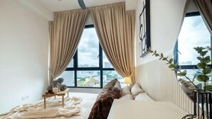 A hotel room with a large window, a bed, a bedside table, and a view of the city. - CUBIC BOTANICAL BY FEEL HOME (Kuala Lumpur)