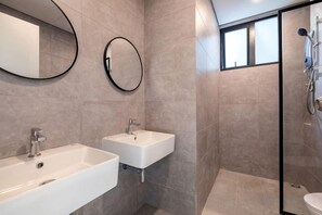 Ein Badezimmer mit zwei Waschbecken, einer Dusche und einer Duschkabine aus Glas.