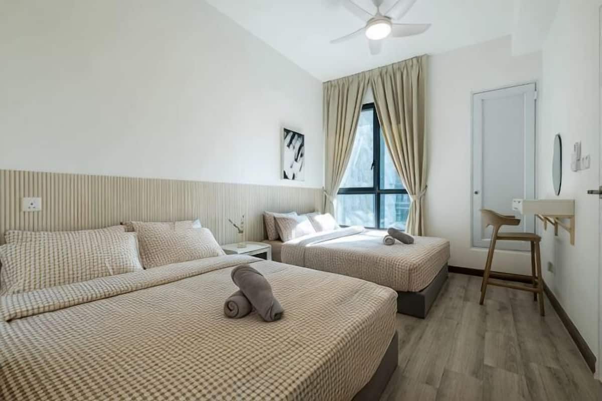 Een hotelkamer met twee bedden, een plafondventilator, een raam met gordijnen, een nachtkastje en een stoel.