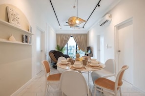 Un coin repas avec une table ronde, des chaises blanches et un luminaire suspendu au design moderne.
