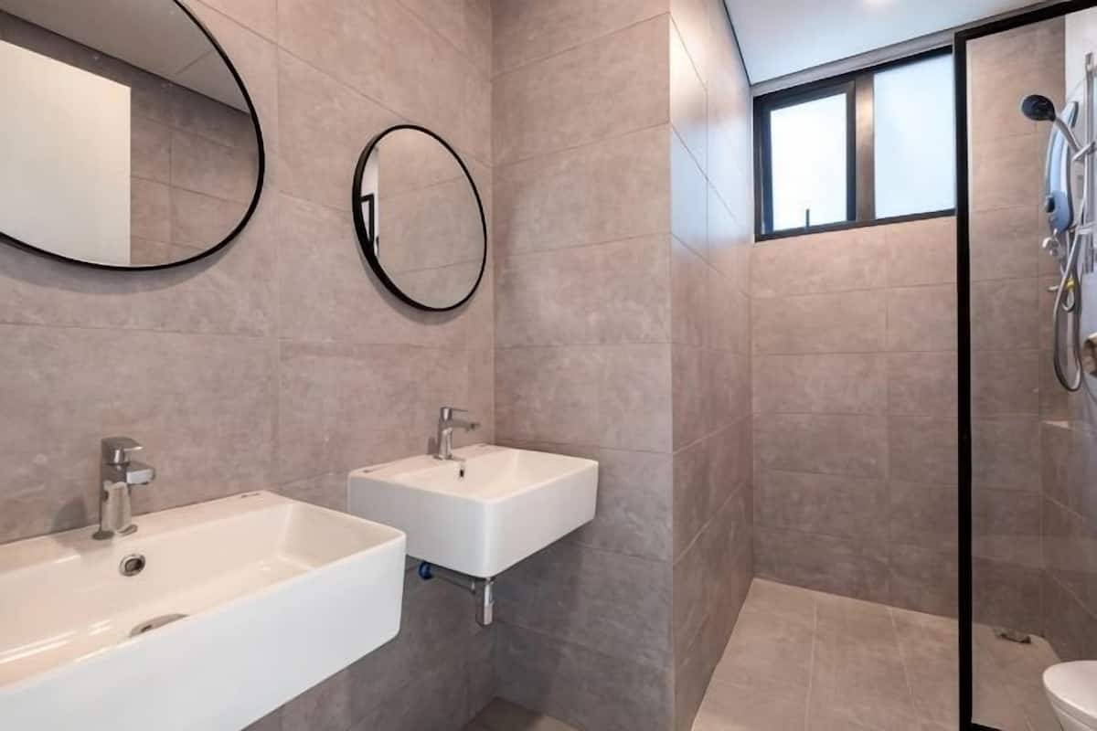 Een badkamer met twee wasbakken, een douche en een grote spiegel.