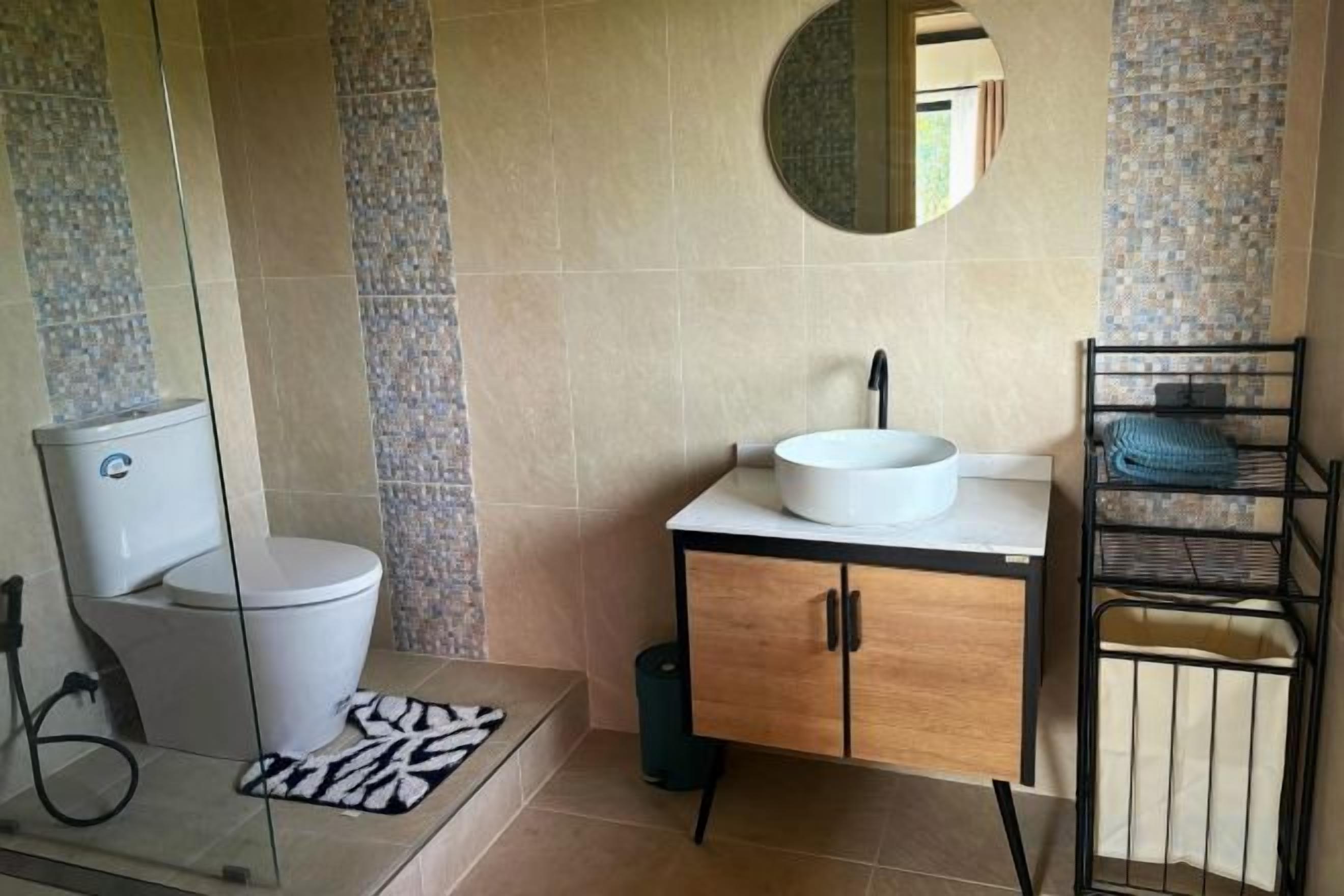 A bathroom with a toilet, sink, and mirror.