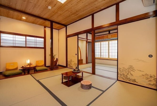 A traditional Japanese room with tatami flooring, sliding doors, and a low wooden ceiling.