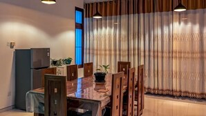 A dining area with a wooden table and chairs, a ceiling fan, and a refrigerator. - Nirosha Guest House (Galle)