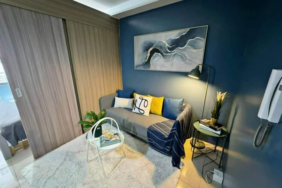 A modern living room with a sofa, a coffee table, a lamp, and a painting on the wall.