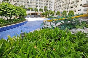 A hotel courtyard with a swimming pool, greenery, and a multi-story building in the background. - Shore Residences MOA staycation (Pasay)