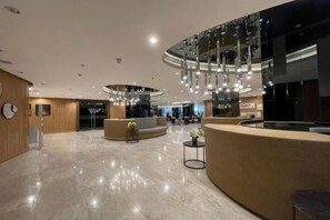 A spacious lobby with a reception desk, seating area, and a modern chandelier. - Shore Residences MOA staycation (Pasay)