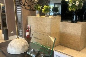 En receptionsdisk med et glasdisplay, en brandslukker og en potteplante.