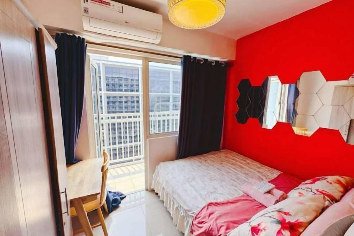 A bedroom with a bed, a window, a chair, and a red wall.