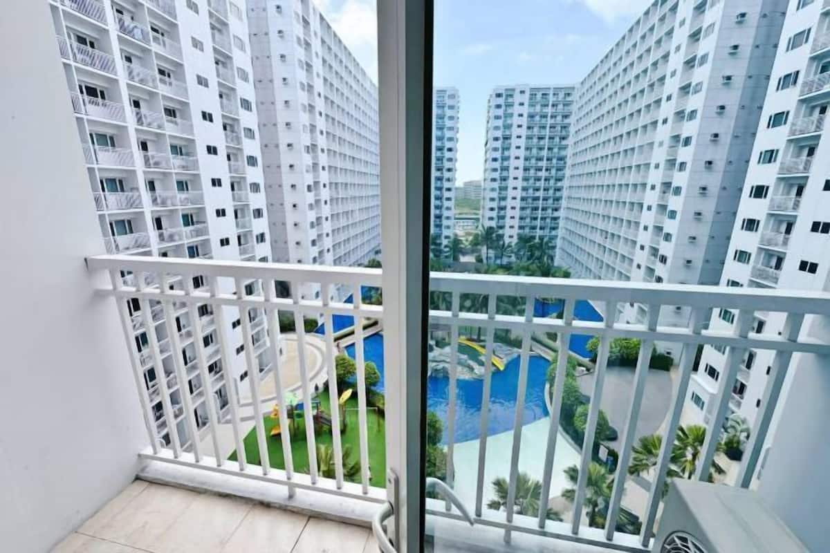 A high-rise residential building with multiple balconies, a central courtyard with a circular walkway, and surrounding greenery.
