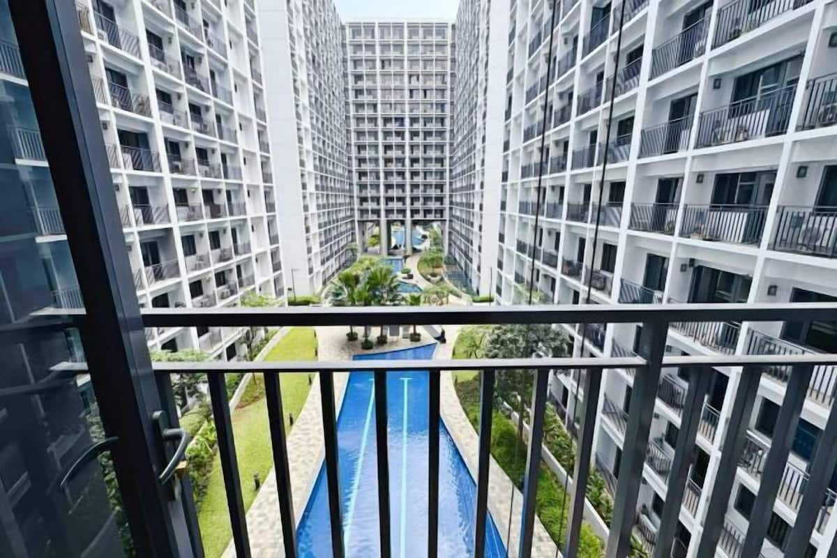 A high-rise residential building with a central courtyard, balconies, and a blue water feature.