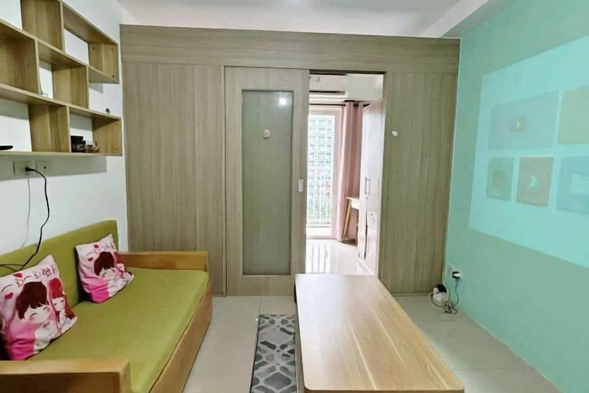 A modern room with a green sofa, a wooden table, and a wall-mounted shelf.