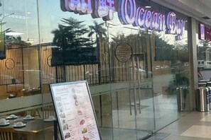 A restaurant with a menu board in front, a glass door entrance, and a view of the outside. - Shore Residences MOA staycation (Pasay)