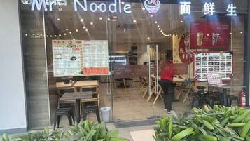 A restaurant named 'Mr. Noodle' with a menu board and seating area visible through the glass.