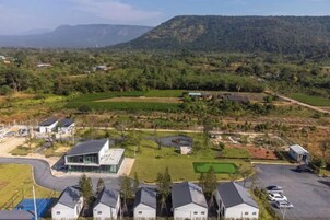 Zona residencial con casas modernas, un edificio grande con fachada de vidrio y un estacionamiento.