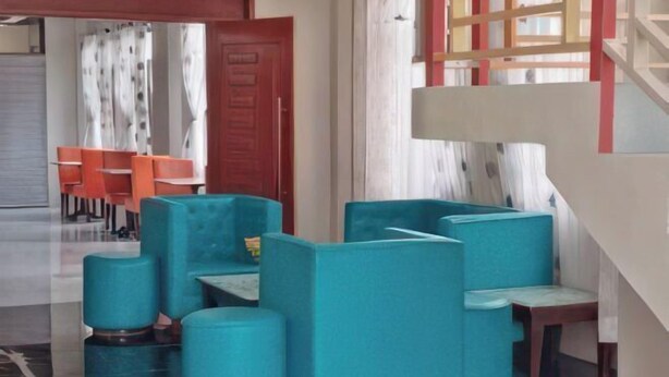 A modern hotel lobby with teal-colored seating, a staircase, and a dining area in the background. - Sunnyside Hotel (Santo Tomas)